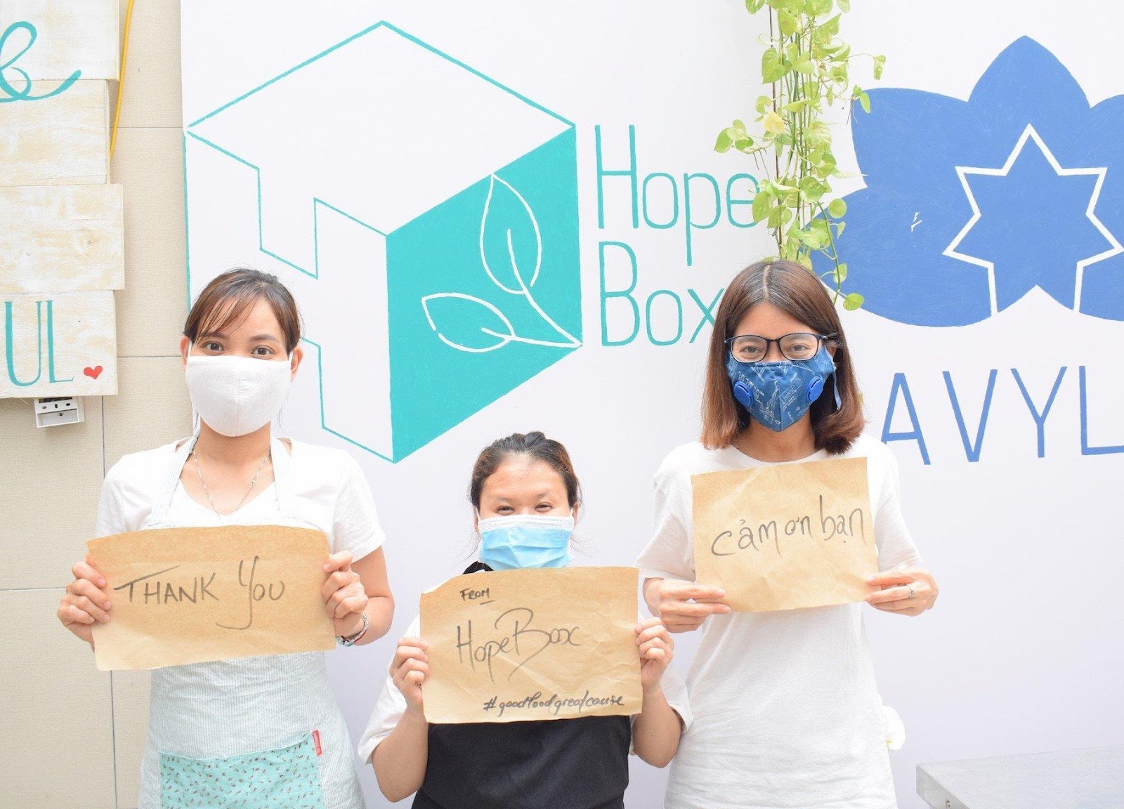 A group of people wearing masks and holding signsDescription automatically generated with low confidence